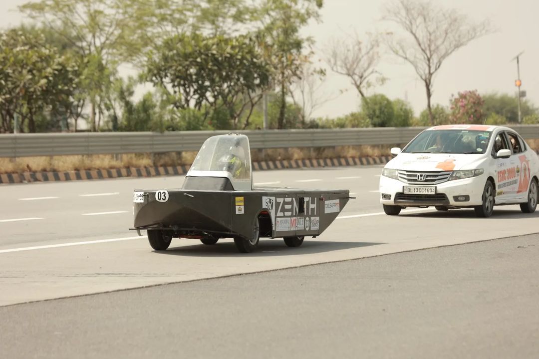 SolarMobil's ZENITH, a red and black single-seater solar car with a bullet-shaped body, ready for competition.